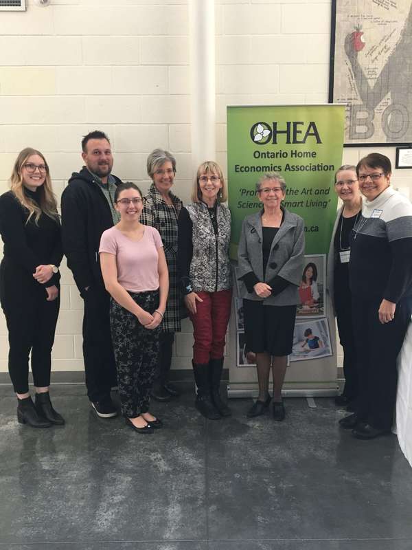 Image of seven women and 1 man smiling at the camera with the OHEA banner behind them