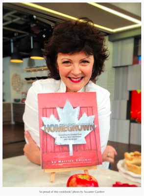 Image of woman smiling with a red cookbook titled Homegrown in front